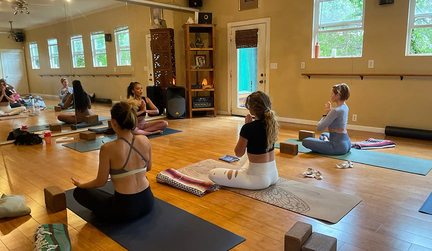 A yoga class seated in meditation in the Maui Yoga Shala studio